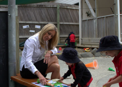 Vision and values gallery, Maria reading to a child by the sandpit